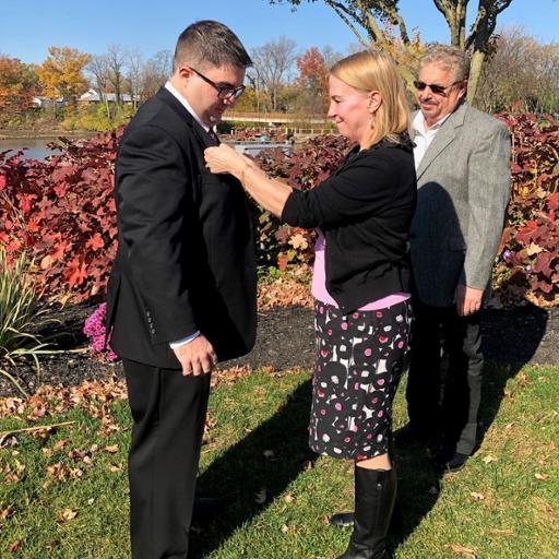 New Berea firefighter Ryan Casey (right) watched as his mother, Kitty Romance, pins the firefighter badge to his suit during his swearing-in ceremony. His stepfather, Tim Romance, is to the left.